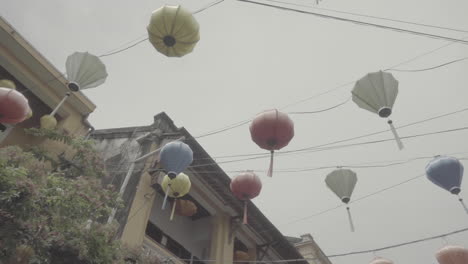 Low-Angle-Aufnahme-Der-Hängenden-Bunten-Lichter-In-Hoi-An,-Vietnam-An-Einem-Wolkigen-Grauen-Tag,-Die-über-Dem-Stadtklotz-Hängen