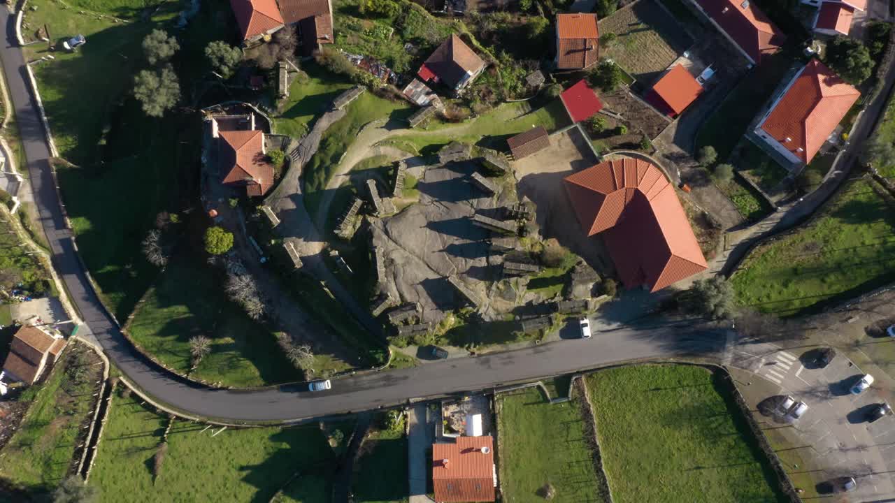 vista del cenital sobre graneros con techos naranjas que proyectan largas sombras en las tierras vacías de la aldea en soajo
