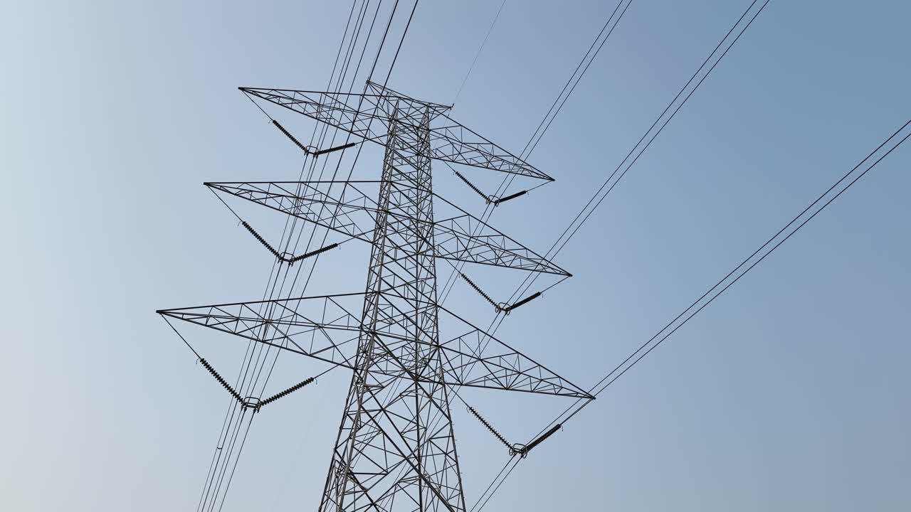 Camera orbits a high voltage electricity transmission tower, revealing power lines and lattice structure that form the backbone of energy distribution networks