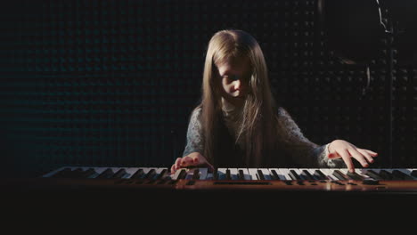 tiny artist plays musical device in recording studio. girl pianist brings melodies to life on synthesizer in musical academy. flourishing of talents