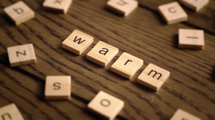 Wooden letter tiles spell the word warm as the camera pans across a wooden surface with cozy lighting.