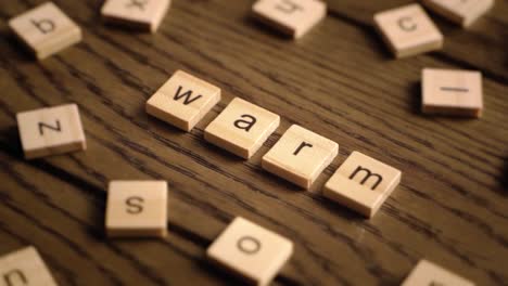 wooden letter tiles spell the word warm as the camera pans across a wooden surface with cozy lighting.