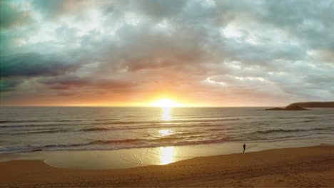 Toma-Aérea-De-Un-Dron-Que-Se-Eleva-Del-Amanecer-En-La-Playa-Con-Un-Corredor-En-El-Puerto-De-Coffs