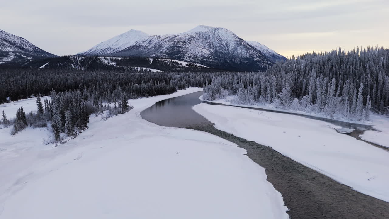 Takhini River Flowing Through Frozen Terrain At Dusk In Yukon Territory, Canada. drone tilt-up shot