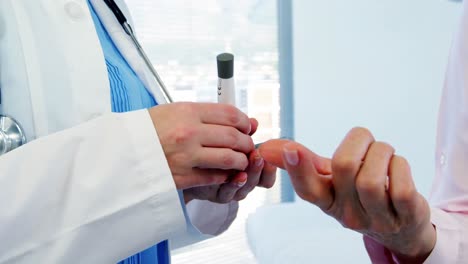 una mujer médico midiendo el nivel de azúcar del paciente con un glucómetro