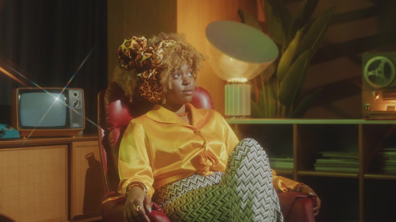 Stylish African-American Woman Sitting in Chair and Posing in Retro Studio