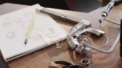 biracial female worker at table with handcraft tools and design in studio in slow motion