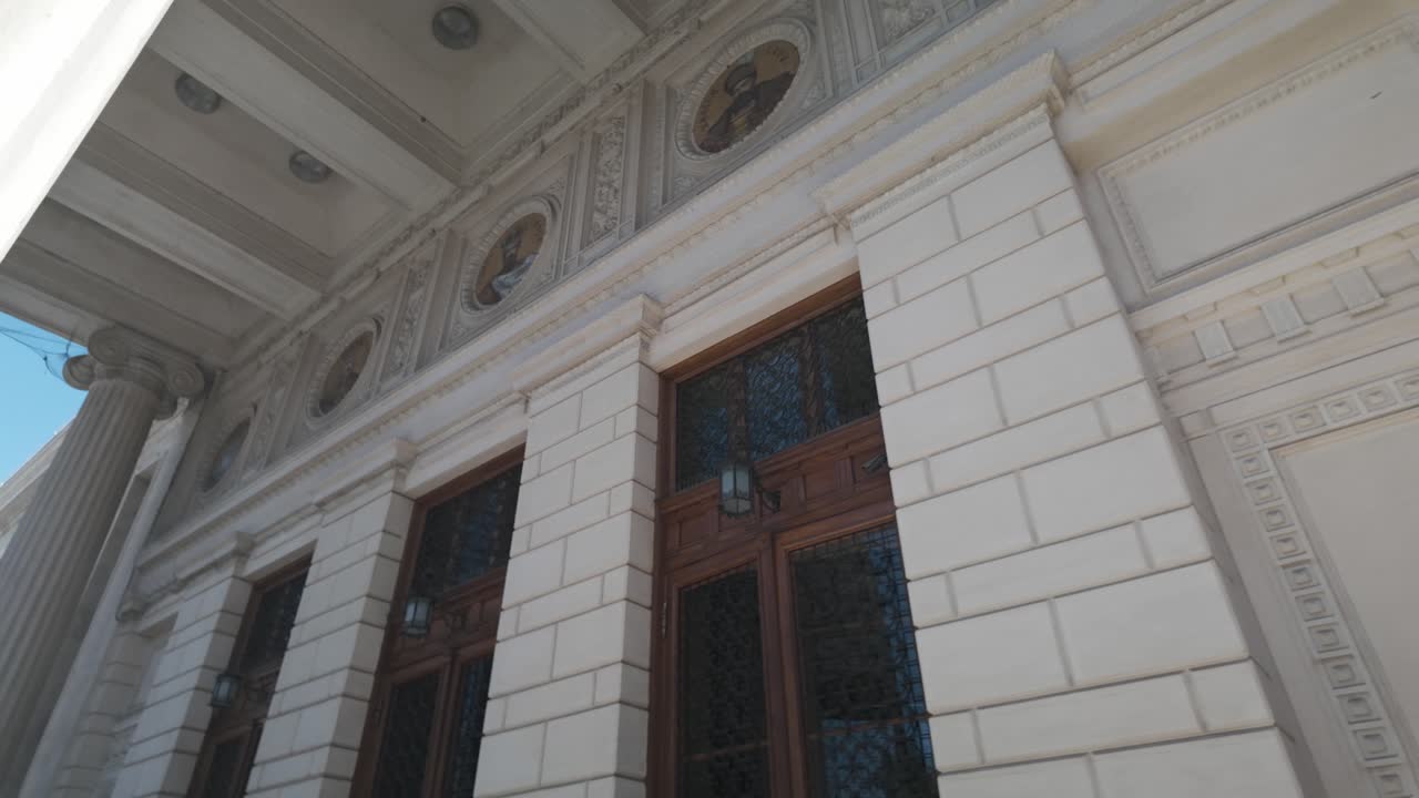 Plano cenital a cámara lenta que avanza a través de columnas clásicas y muestra la entrada principal del Ateneo Rumano en Bucarest