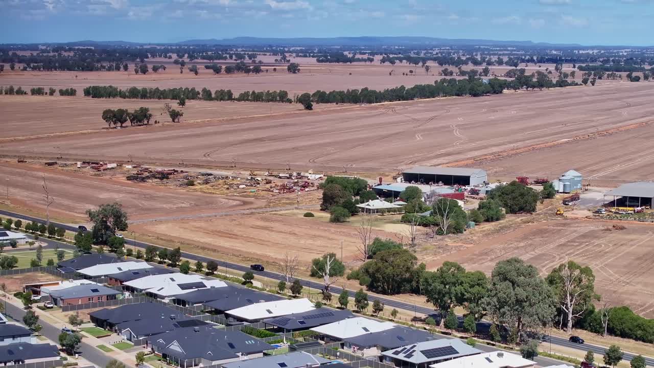 Over new housing and towards rusting old farm equipment beside the Midland Highway near Yarrawonga Victoria Australia