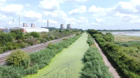 Grünalgenbedeckte-Kanalwasserstraße,-Die-Zur-Luftdrohnenansicht-Der-Kraftwerksindustrie-Führt,-Ziehen-Sich-Schnell-Zurück