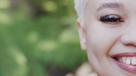 retrato de una feliz mujer biracial en el jardín con grandes hojas verdes en cámara lenta
