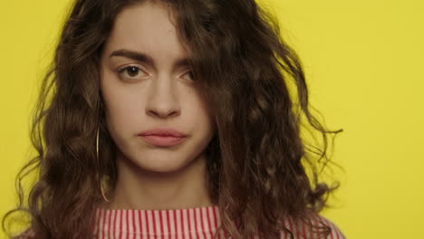 Close-up-of-sad-girl-face.-Offended-woman-looking-to-camera-on-yellow-background