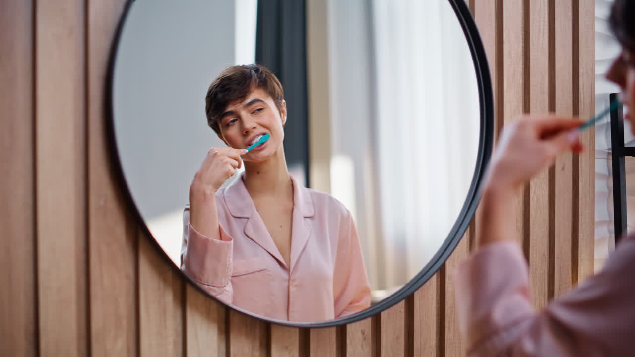 Brushing teeth lady morning at bathroom closeup. Happy woman cleaning mouth