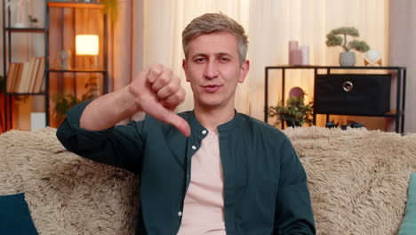 young man shows thumbs down gesture with serious expression showing disapproval or disagreement