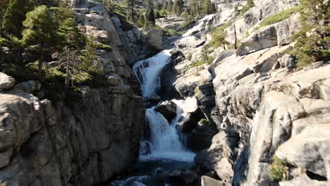 stabilized 4k cinematic drone flies through the rocky cliffs of an epic waterfall in the desolation wilderness of lake tahoe area in california and nevada