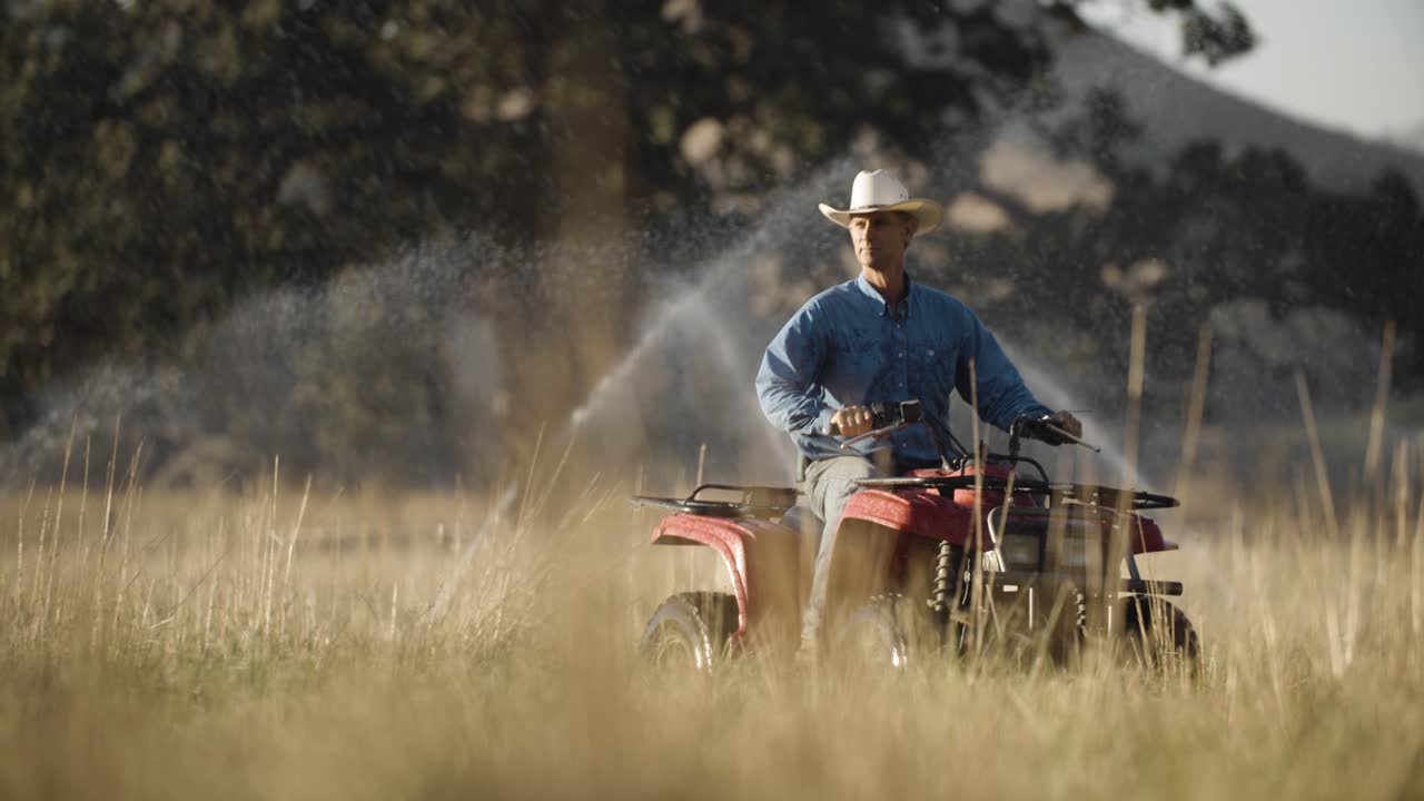 Rancher riding ATV through his field that's being watered