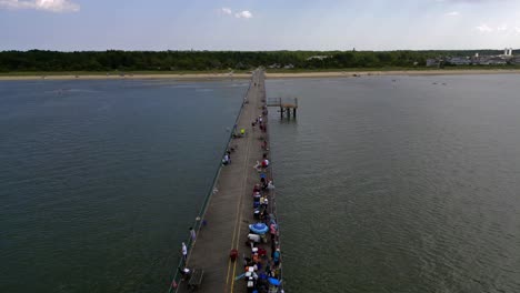 an aerial view of a long fishing pier on delaware bay in the shadow of clouds