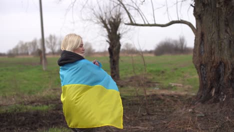 woman flag of ukraine near burnt tree