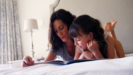 Madre-E-Hija-Leyendo-Un-Libro-Mientras-Están-Acostadas-En-La-Cama-En-El-Dormitorio