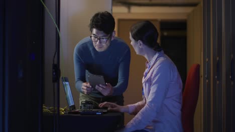 diverse female and male it technicians using laptop checking computer server