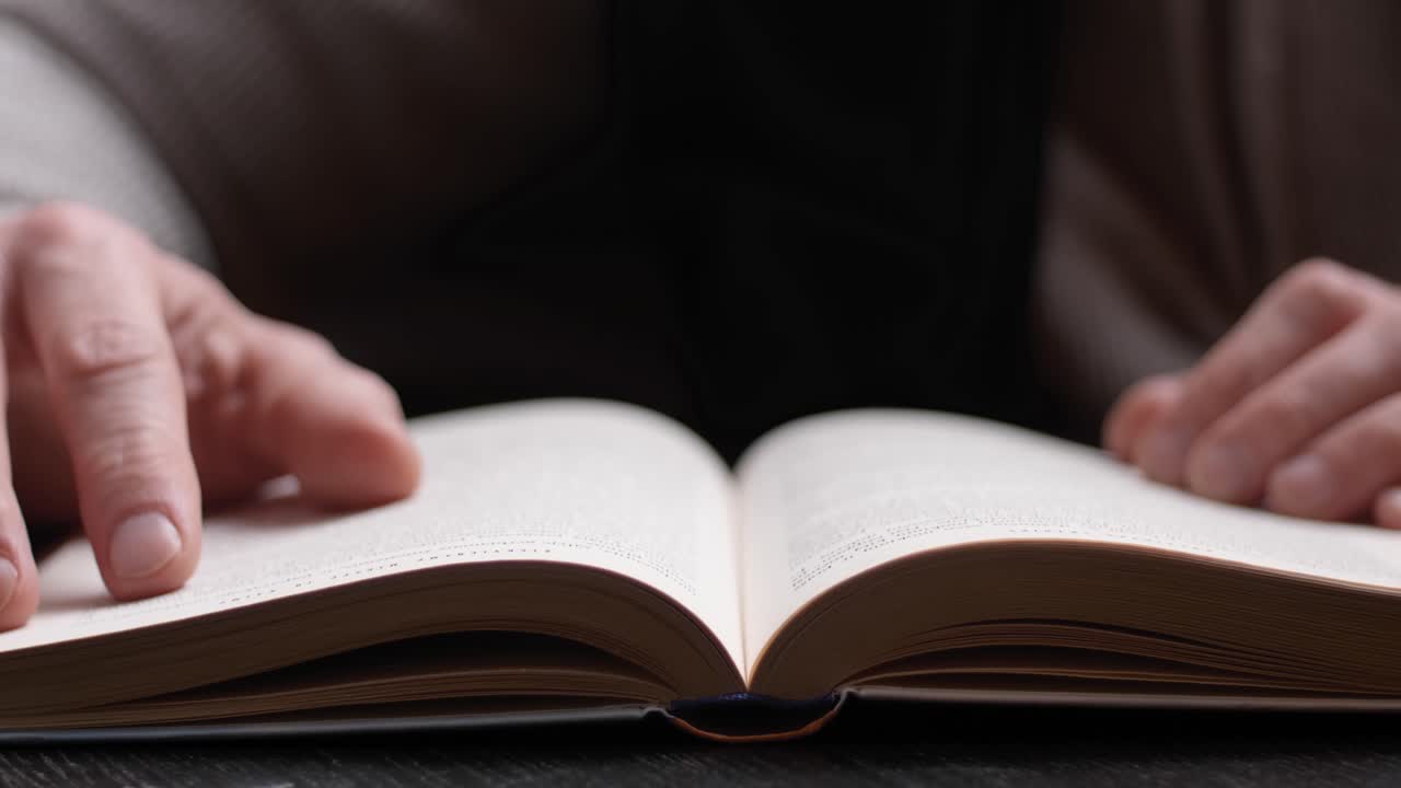 Unrecognizable person reading a book. Hand Turning Pages of a Book, close up.