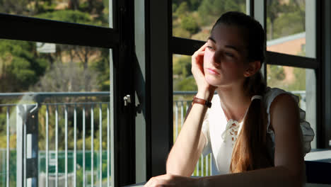 thoughtful schoolgirl looking through window