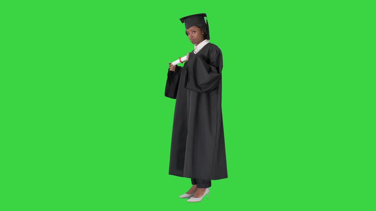 Studentessa afroamericana sorridente in toga da laurea che posa con il diploma su schermo verde, Chroma Key