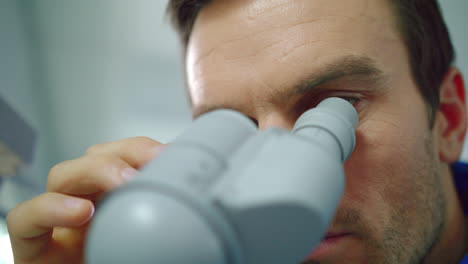 scientist face looking microscope. close up of scientist looking microscope