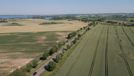 Eine-Romantische-Landstraße-Mit-Bäumen-Auf-Der-Linken-Und-Rechten-Seite-Schlängelt-Sich-Durch-Die-Masuren-In-Polen-–-Ein-Romantischer-Kameraflug-Aus-Der-Vogelperspektive-Zeigt-Die-Atemberaubende-Landschaft