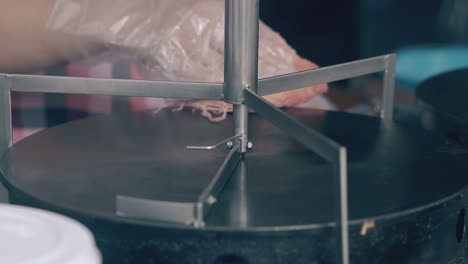 chef cleans crepe maker with water and rag in cafe closeup