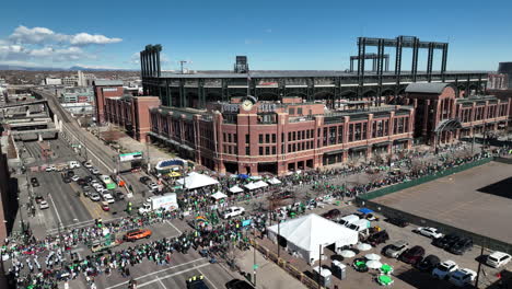 Drone-shot-of-the-Saint-Patrick's-Day-parade-passing-by-Coors-Field-in-Denver,-Colorado