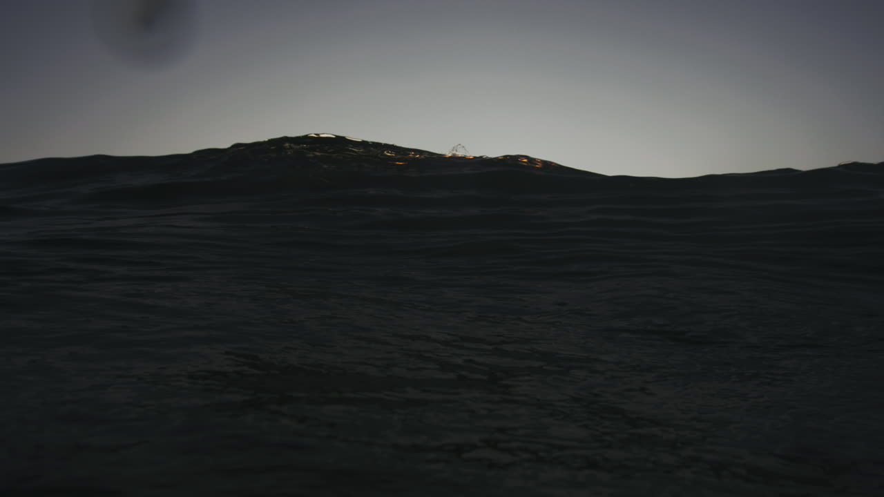 vista frontal de la zona de impacto de la onda que choca y refracta la luz verde dorado en agua clara