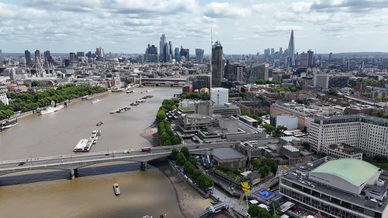 Aerial drone footage gliding east along River Thames, capturing stunning views of Waterloo Bridge with the City of London’s skyline shimmering in the distance.