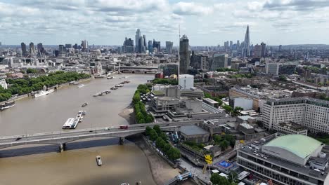 aerial drone footage gliding east along river thames, capturing stunning views of waterloo bridge with the city of london’s skyline shimmering in the distance.