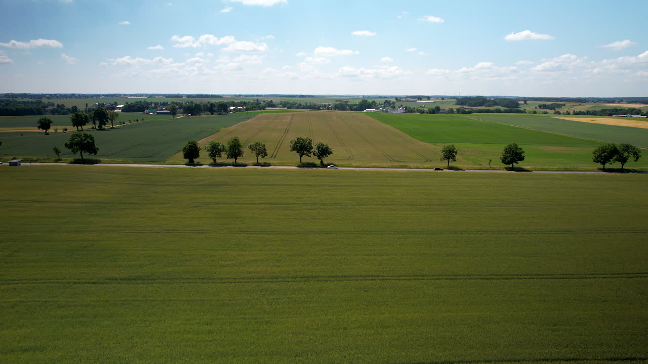 los coches conducen por la carretera del país pasando por exuberantes tierras de cultivo verdes en el campo, aérea