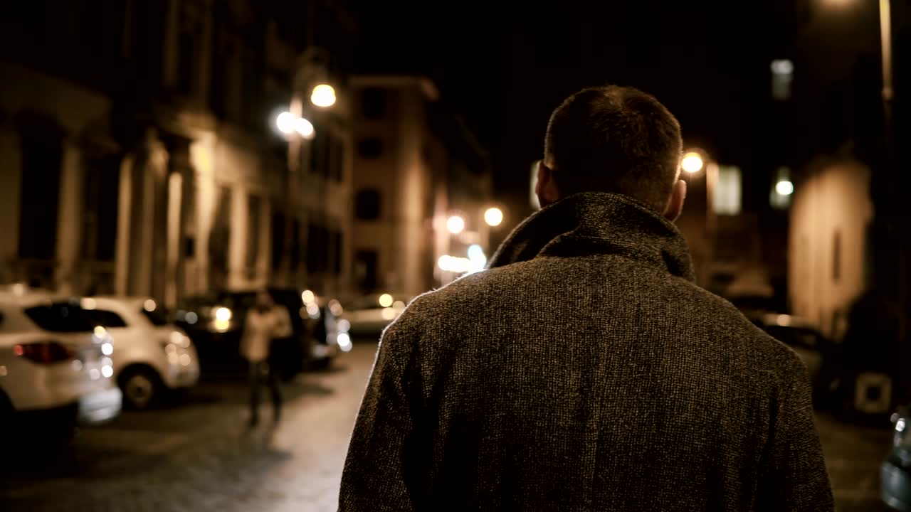 задний вид молодого стильного человека, идущего по пустынной дорожке в одиночку и размышляющего вечером.