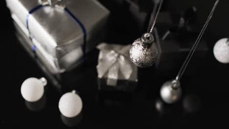 video of silver baubles christmas decorations and presents with copy space on black background