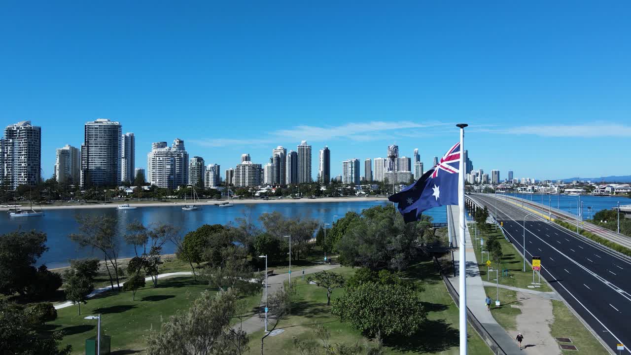 Unique View Of A Flag Waving In A Strong Breeze Above A Park With A Modern Architectural Skyline