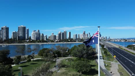 unique view of a flag waving in a strong breeze above a park with a modern architectural skyline backdrop