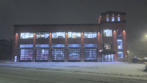 heavy snowfall at night outside fire station in city of magog, quebec, canada. wide static shot
