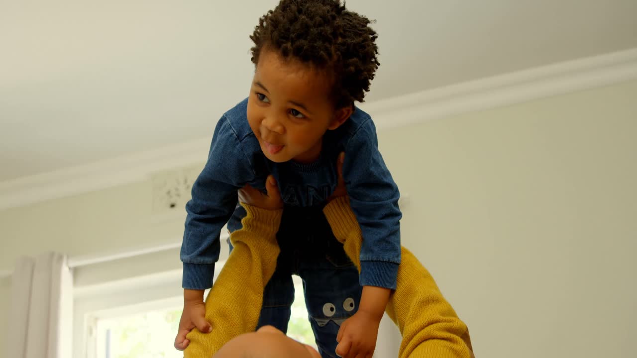 Rear view of young black mother playing with her son in a comfortable home 4k