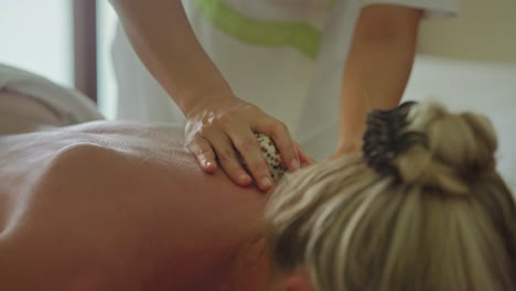 masseuse doing a maldivian cowrie shell massage on clients back, relax