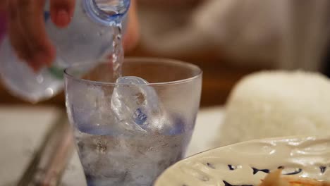 water being poured into a glass with ice