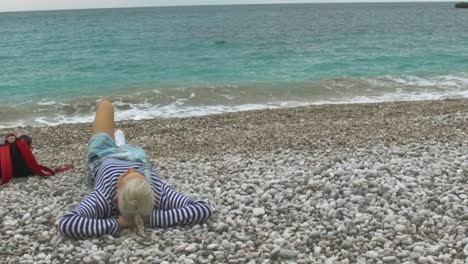 woman relaxing on a pebble beach