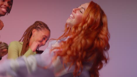 studio shot of young gen z friends dancing at club against pink background 7