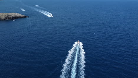 Speedboats-trailing-in-blue-waters-of-Polignano-a-mar,-Italy