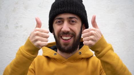 close up of a man with unshaven face showing a two hand thumbs up with a smile