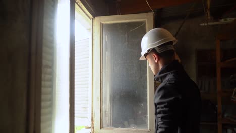 side portrait of young architect checking out old window of a house for renovation