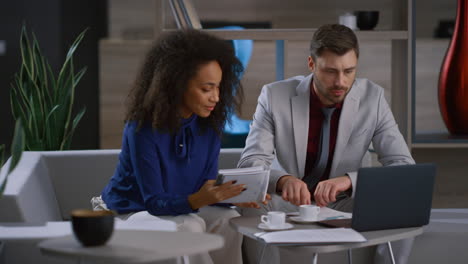 Multiracial-coworkers-team-discuss-marketing-project-using-laptop-in-cafe-office