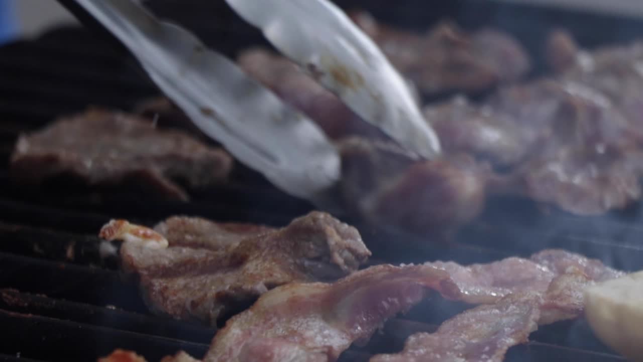 ⁇ 에 고기와 베이컨을 요리하는 셰프가 천천히 음식을  ⁇ 으로 돌려  ⁇ 게 요리합니다.